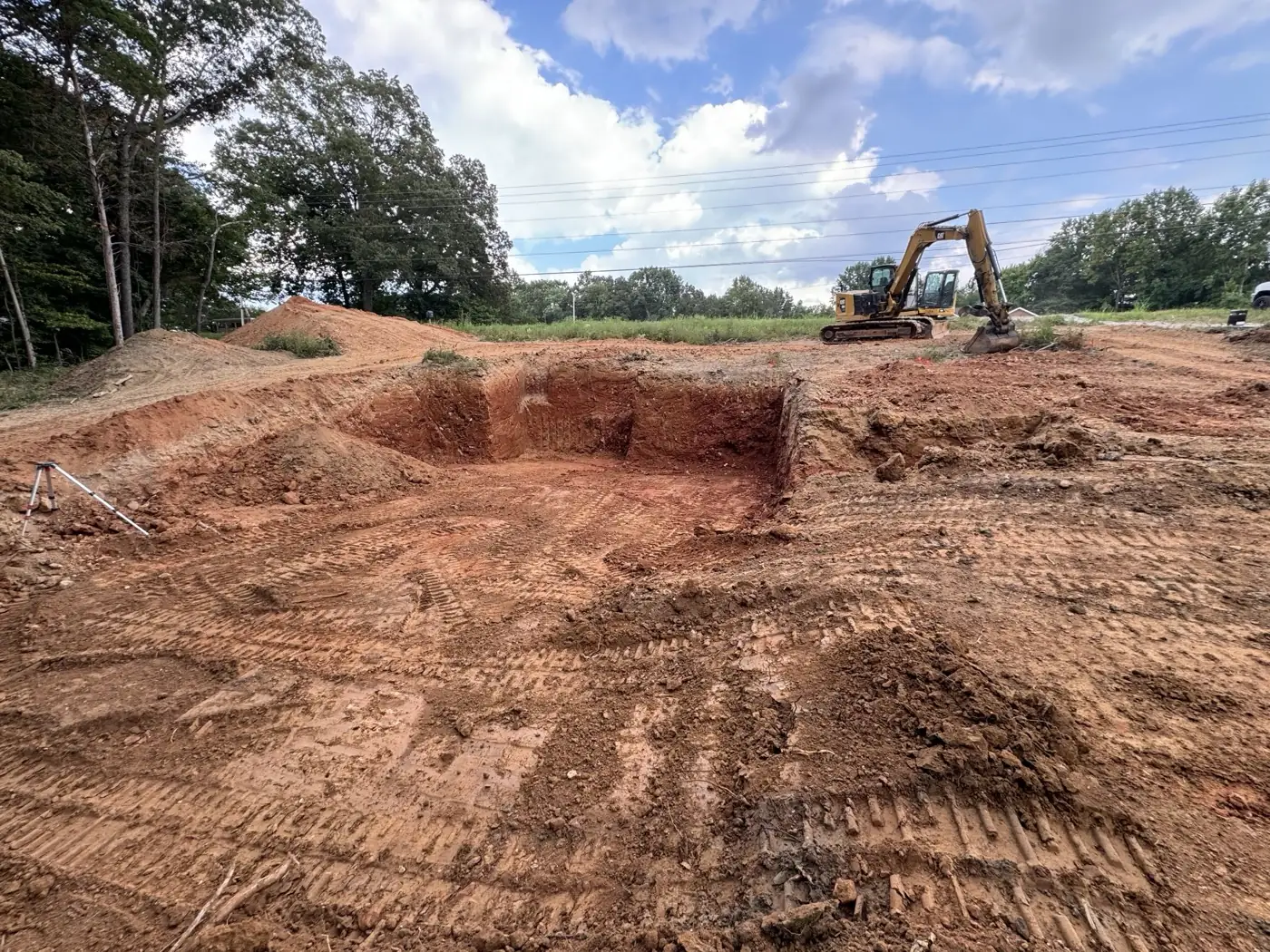 Excavator digging a foundation in red clay