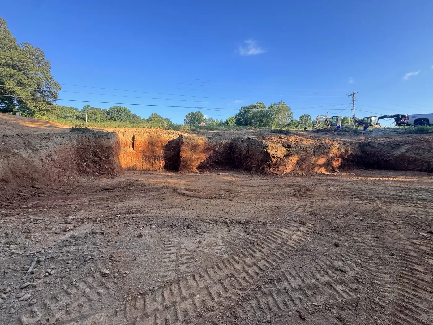 Open excavation cut into red clay on a job site