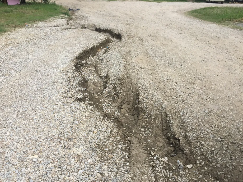Runoff washout cut down the middle of a gravel driveway
