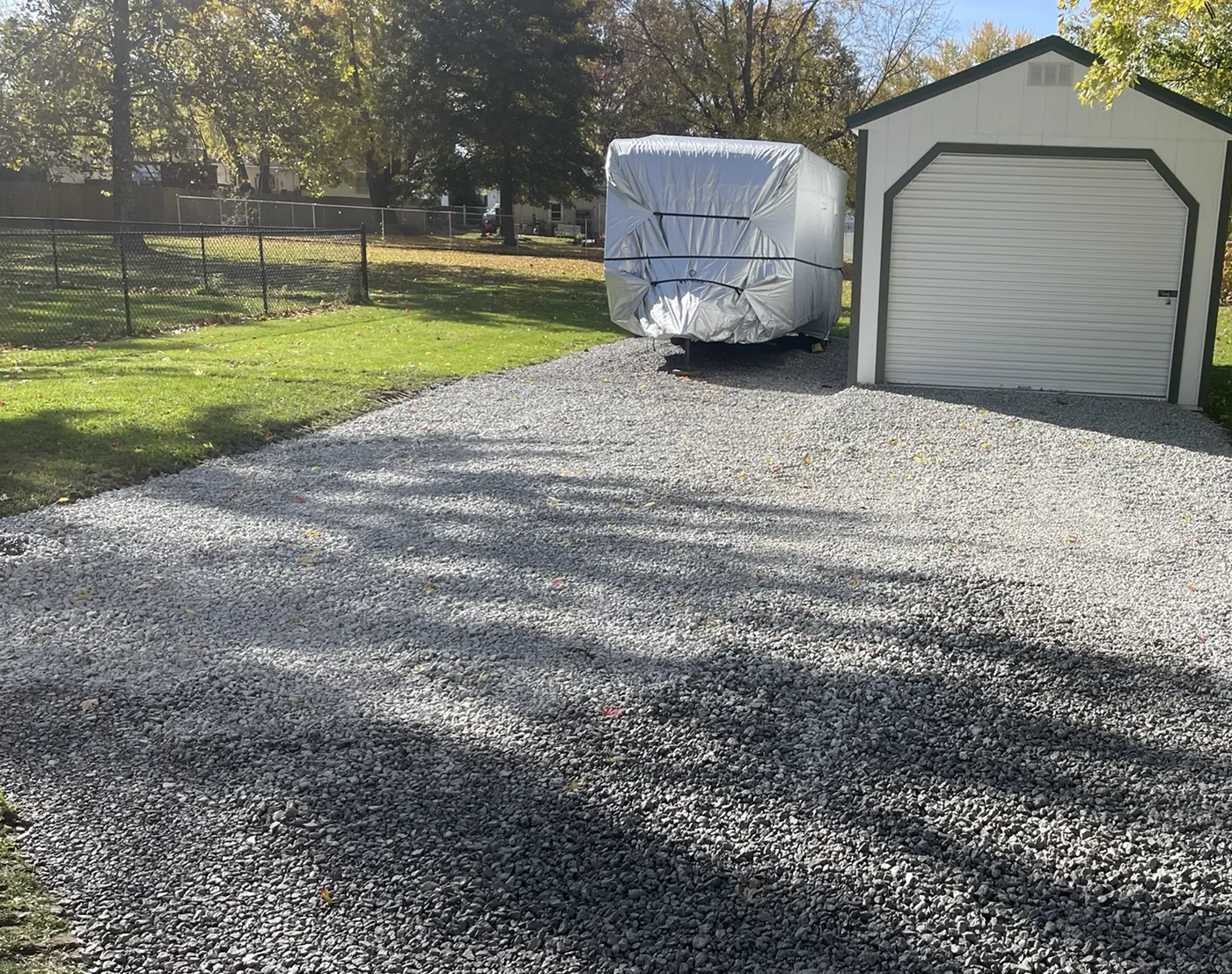 New gravel driveway and parking pad packed in front of a garage