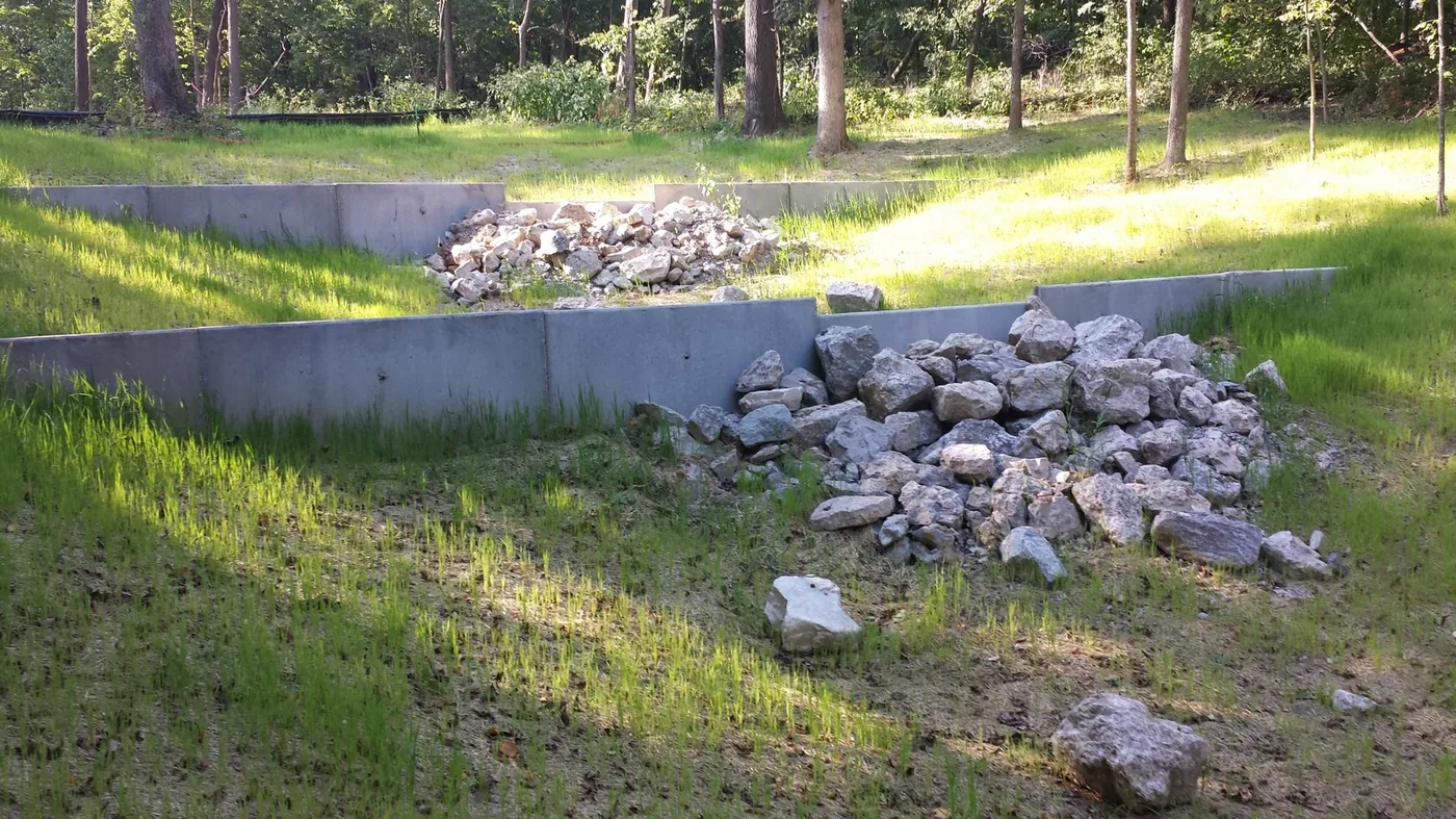 Rock check dams slowing water in a grassed drainage swale