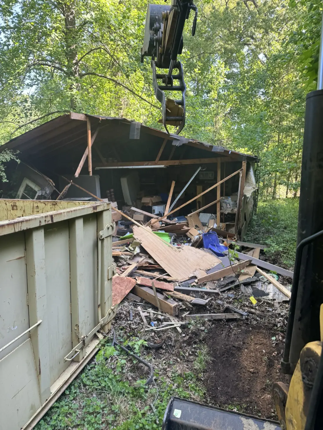 Old shed coming down, with debris loaded into a roll off container