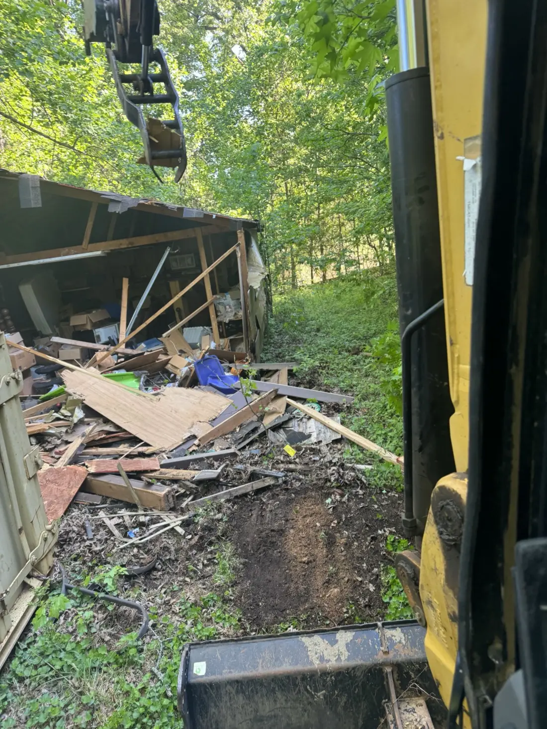 Teardown debris staged for loading, seen from the excavator cab