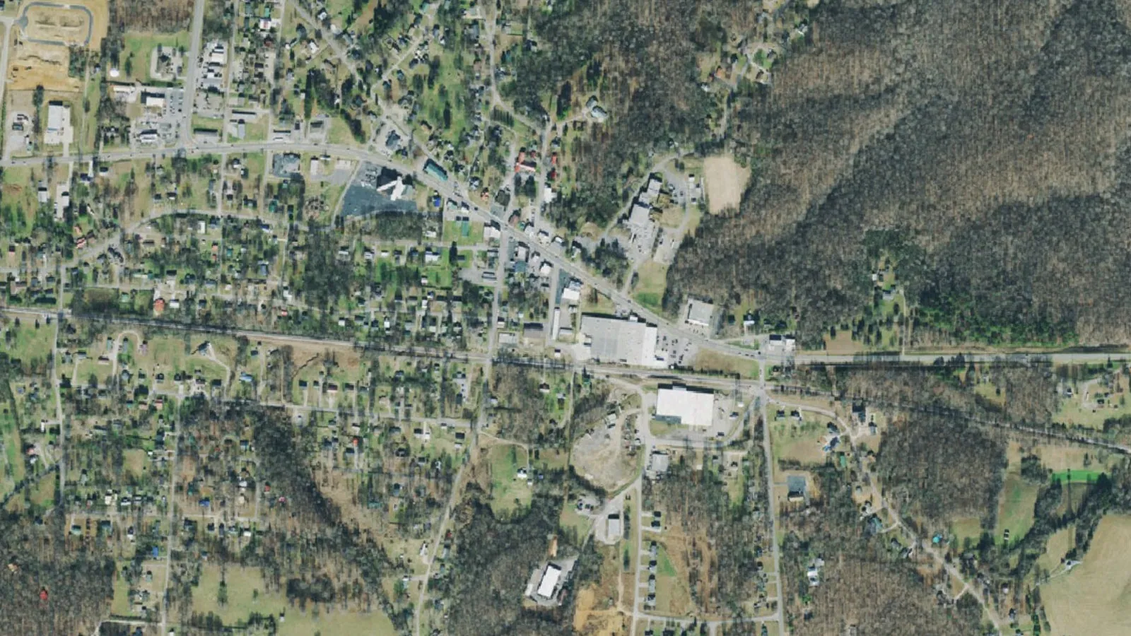 Aerial view of White Bluff, Tennessee, with homes and streets below a wooded ridge on the east side of town